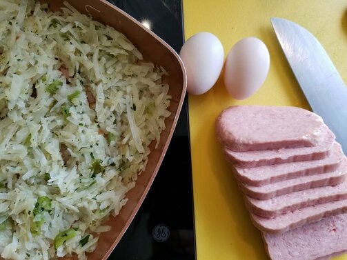 Photo of homemade potatoes O'Brien and spam and eggs and a knife about to be cooked for a meal